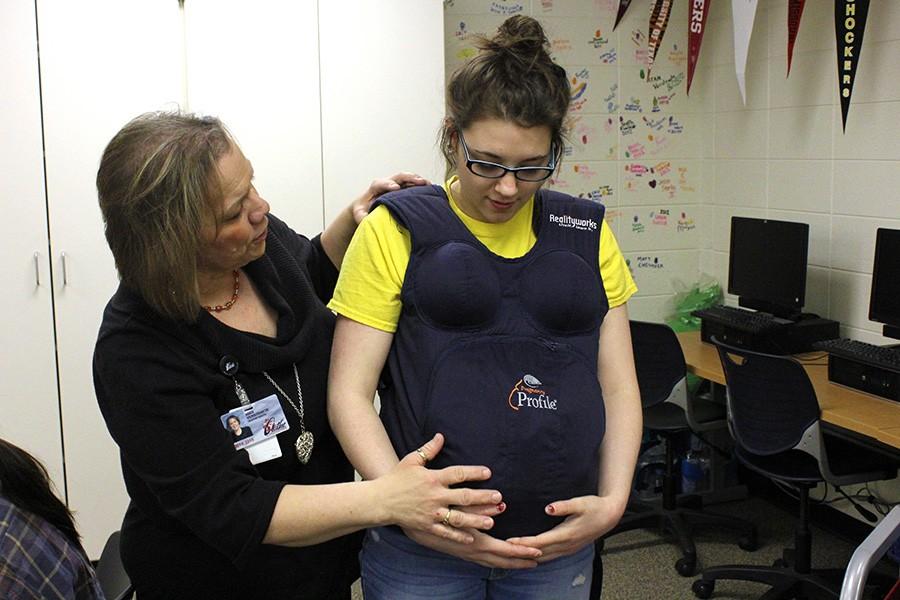 Angie Verstraete, FACS teacher, assists a student in fitting the empathy belly.