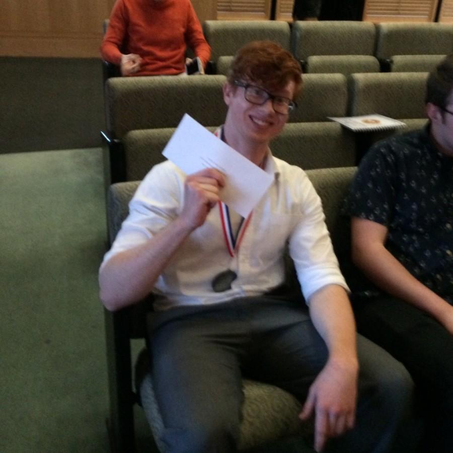 Liam Chewning, junior, holding his award and showcasing his medal for winning second place. 