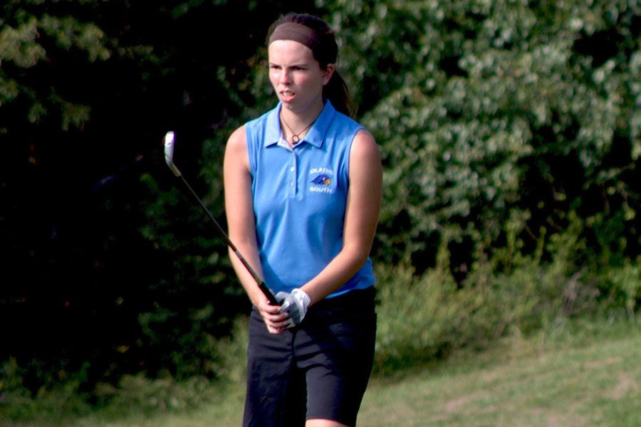 Claire Beeler, senior, lines up her golf ball for another swing at a golf match during the season.