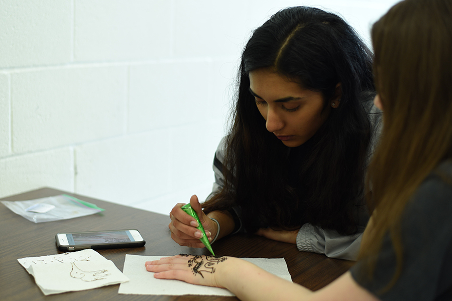 Prutha Gajakas, sophomore, uses henna to decorate a hand.