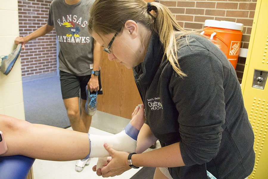 New physical trainer, Jordin Brouhard, applies a bandage to a students ankle after having pre-wrapped it in an attempt to support her as she runs. 