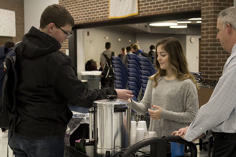 Sonny Varela, senior, serves coffee to a student in front of the Falcon’s Nest in the commons.  Students are able to get coffee early in the mornings before classes begin. The school has provided Verela with the necessary supplies for the small coffee booth and will continue through the end of the year if success is maintained. 