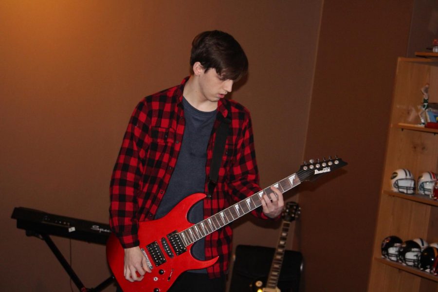 Justin Goodwin, junior, pictured here practicing guitar for his upcoming gig with his band.