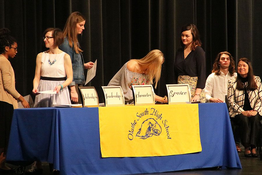 Students signing and accepting their certificate at the NHS induction ceremony.